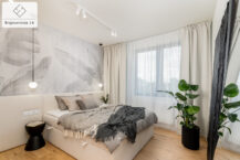 Mieszkanie na sprzedaż Kraków Bronowice - przytulna sypialnia z dużym łóżkiem w jasnej tapicerce, z miękkimi poduszkami i kocami.