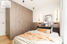 Sypialnia w apartamencie na sprzedaż Kraków Wola Justowska z dużym łóżkiem i dekoracjami.